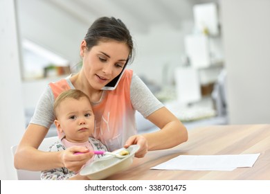 Busy Mother On The Phone Feeding Baby A The Same Time