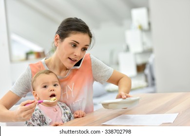 Busy Mother On The Phone Feeding Baby A The Same Time