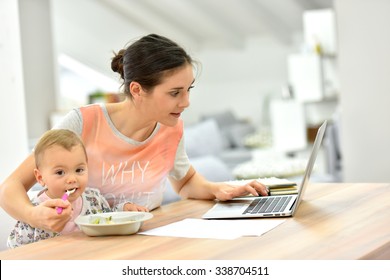 Busy mother trying to work and feed kid at the same time