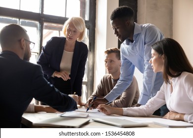 Busy multiethnic old and young businesspeople group working together planning corporate startup project in teamwork analyze financial report discussing marketing result at team office briefing table - Powered by Shutterstock