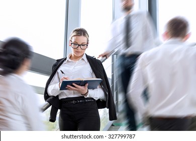 Busy Office Building Corridor, Three Business People In A Motion, Focus On Woman Standing And Taking Notes