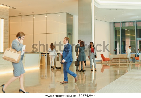 Busy office lobby with business people walking\
and talking