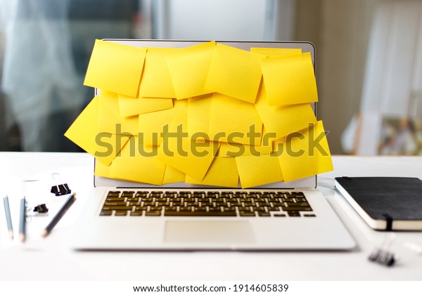 Busy office working lifestyle\
concept with Laptop screen covered by yellow sticky\
notes.