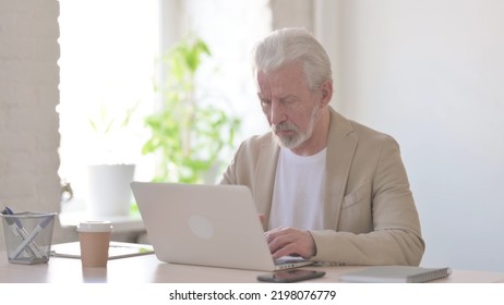 Busy Old Man Using Laptop In Office