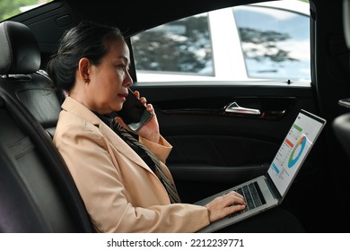 Busy Senior businesswoman having phone conversation and checking data on laptop while sitting in back passenger seat, Rush hour in car concept. - Powered by Shutterstock