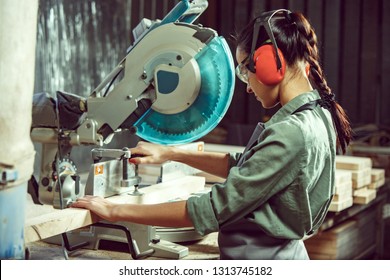 Busy And Serious Craftswoman Grinding Timbers With Special Machine. Beautiful Woman Wearing Safety Glasses. Concept Of Joiner's Shop And Woodworking. Gender Equality. Male Profession