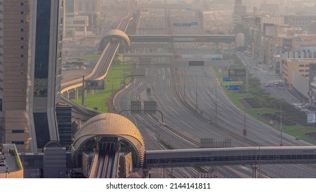 Busy Sheikh Zayed Road Aerial Timelapse, Metro Railway And Modern Skyscrapers Around In Luxury Dubai City With Evening Haze. Heavy Traffic On A Highway With Many Cars. United Arab Emirates