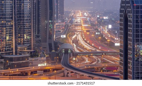 Busy Sheikh Zayed Road Aerial Day To Night Transition Timelapse, Metro Railway And Modern Skyscrapers Around In Luxury Dubai City. Heavy Traffic On A Highway With Many Cars. United Arab Emirates