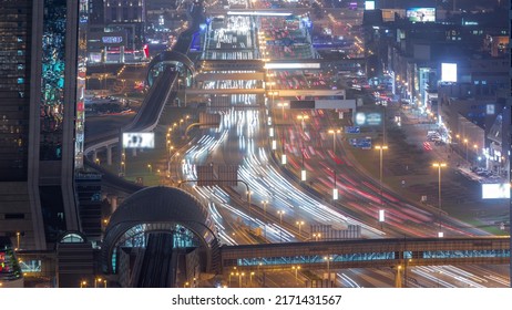 Busy Sheikh Zayed Road Aerial Night Timelapse, Metro Railway And Modern Skyscrapers Around In Luxury Dubai City. Heavy Traffic On A Highway With Many Cars. United Arab Emirates