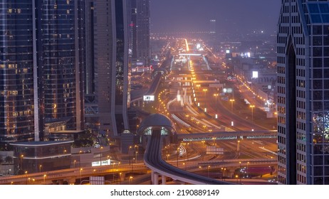 Busy Sheikh Zayed Road Aerial Night To Day Transition Timelapse, Metro Railway And Modern Skyscrapers Around In Luxury Dubai City. Heavy Traffic On A Highway With Many Cars. United Arab Emirates