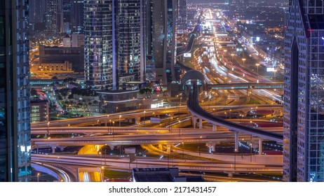 Busy Sheikh Zayed Road Intersection Aerial Night Timelapse, Metro Railway And Modern Skyscrapers Around In Luxury Dubai City. Heavy Traffic On A Highway Junction With Many Cars. United Arab Emirates