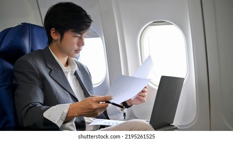 Busy and smart young Asian businessman or male executive manager working and checking his business paperwork during the flight on his private jet. - Powered by Shutterstock