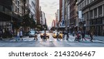 Busy street scene with crowds of people walking across an intersection on Fifth Avenue in New York City NYC