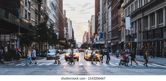 Busy street scene with crowds of people walking across an intersection on Fifth Avenue in New York City NYC