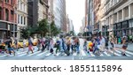 Busy street scene in New York City with groups of people walking across a crowded intersection on Fifth Avenue in Midtown Manhattan NYC
