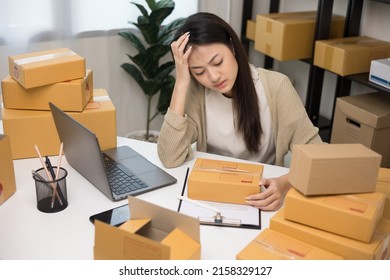 Busy And Stressed Asian Entrepreneur Woman Checking Product On Stock Working With Laptop. Business Woman Working SME Online At Home. Small Business Owner Start Up Freelance Concept.