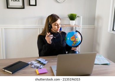 Busy Travel Agent With A Headset Holding A Globe While Speaking With Clients Online 