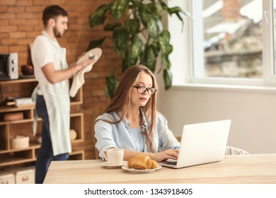 Busy Wife Working While Her Husband Doing Chores At Home