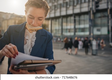 Busy woman is in a hurry, she does not have time, she is going to eat snack on the go. Worker eating and talking on the phone at the same time..  Business female person. - Powered by Shutterstock