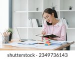 The busy work desk of a businesswoman is cluttered with stacks of paper files, folders, and papers as she searches and checks for unfinished documents, her hands moving swiftly over the paperwork