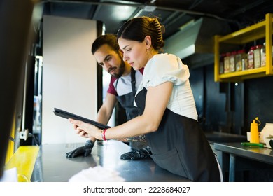 Busy workers at the food truck checking the customers orders in the delivery app on a tablet  - Powered by Shutterstock