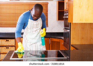 Busy Young African Man Cleaning Cooktop At Home