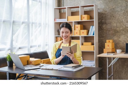 Busy Young Asian Entrepreneur Woman Checking Product On Stock Take Note With Clipboard. Businesswoman Working SME Online At Home. Small Business Owner Start Up Freelance SME Concept.