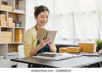 Busy Young Asian Entrepreneur Woman Checking Product On Stock Take Note With Clipboard. Businesswoman Working SME Online At Home. Small Business Owner Start Up Freelance SME Concept.