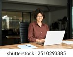 Busy young business woman executive using laptop in office. Smiling Hispanic businesswoman company employee sitting at work desk, professional female hr manager looking at pc computer at workplace.