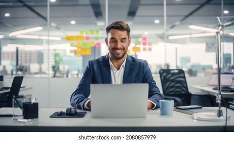 Busy Young Businessman Using Laptop Computer in Modern Office. Manager Thinks About Successful Financial Ideas. Happy Man Smiling About Finding Problem Solving Solutions for Company. - Shutterstock ID 2080857979