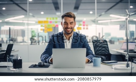 Busy Young Businessman Using Laptop Computer in Modern Office. Manager Thinks About Successful Financial Ideas. Happy Man Smiling About Finding Problem Solving Solutions for Company.