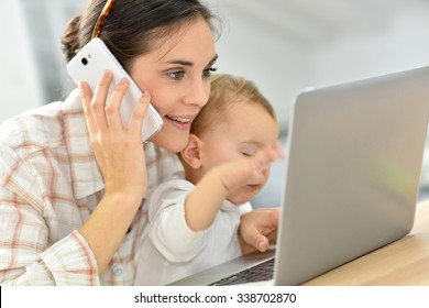 Busy Young Businesswoman Working On Laptop, Baby On Lap