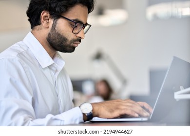 Busy Young Indian Or Arab Professional Business Man Software Engineer, Male Manager Worker Using Laptop Computer Working In Office Analyzing Data Technology Typing Sitting At Workplace.