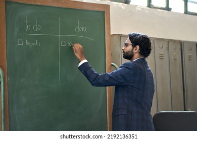 Busy young indian business man working standing in office writing project plan tasks on blackboard. Arab executive making checklist of tasks to do and done. Corporate organization management concept - Powered by Shutterstock