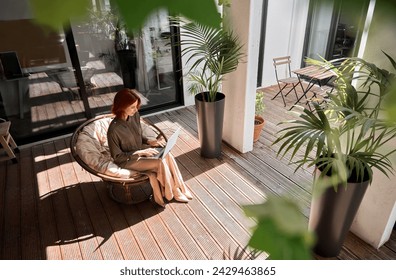 Busy young professional red-haired business woman entrepreneur or worker holding laptop using computer working sitting in cozy chair in sunny creative green office environment. Top view from above - Powered by Shutterstock