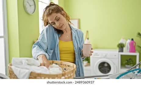 Busy young woman multitasking in a modern laundry room while chatting on the phone and holding a mug - Powered by Shutterstock