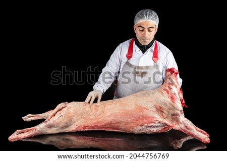 Butcher carrying lamb carcass. Professional male butcher cutting lamb carcass in butcher shop Raw meat. Free space for text.