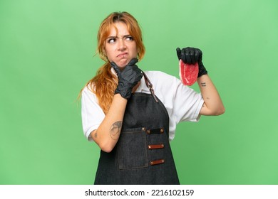 Butcher Caucasian Woman Wearing An Apron And Serving Fresh Cut Meat Isolated On Green Screen Chroma Key Background Having Doubts