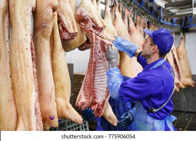 Butcher cutting pork  at the meat manufacturing.