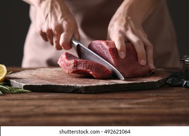 Butcher cutting pork meat on kitchen - Shutterstock ID 492621064