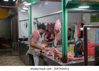 A Butcher In A Face Mask Cutting Meat In A Butcher Shop