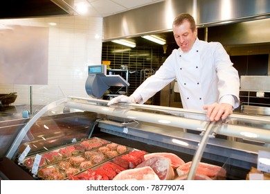 A Butcher At A Fresh Meat Counter In A Grocery Store