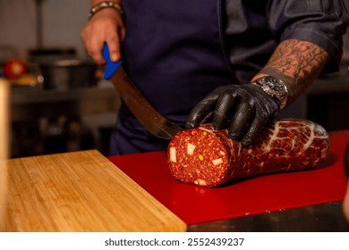 Butcher hands that slicing handmade sausage in a butchers kitchen. Male hands placing a sausage on the cutting table. - Powered by Shutterstock