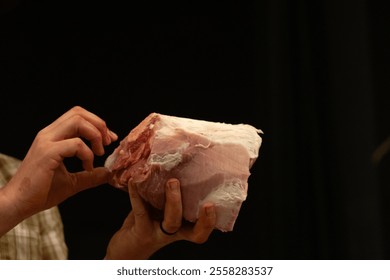 A butcher inspecting a raw pork cut during a butchering demonstration - Powered by Shutterstock