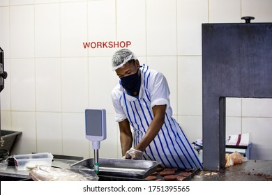 Butcher Preparing Burgers Patty At A Butchery Shop, Saw Cutting Frozen Meat, Using A Mask For Protection