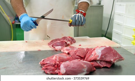 Butcher Sharpening Knife on Sharpening Steel.  Raw meat cuts on a table.
Fresh raw pork chops in meat factory. Meat processing in food industry.  - Powered by Shutterstock