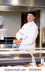 A Butcher Standing Behind A Fresh Meat Counter