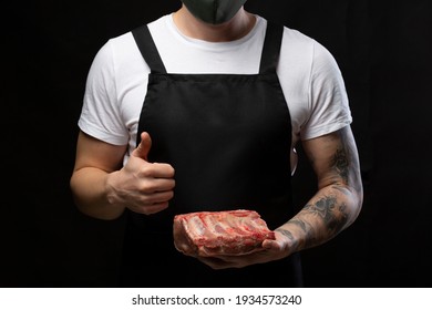 A butcher wearing apron uniform with a piece of pork rib showing thumbs up. - Powered by Shutterstock