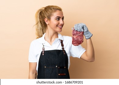 Butcher Woman Wearing An Apron And Serving Fresh Cut Meat Over Isolated Background Looking To The Side