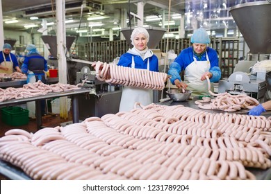 Butchers Processing Sausages At Meat Factory.